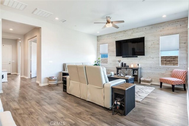 living room with a ceiling fan, visible vents, baseboards, and wood finished floors