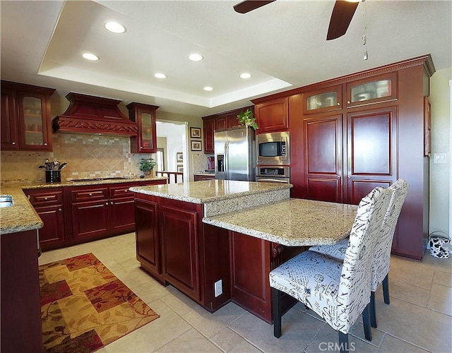 kitchen featuring stainless steel appliances, a raised ceiling, custom exhaust hood, and dark brown cabinets