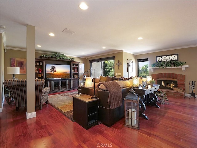 living area with a brick fireplace, ornamental molding, and wood finished floors