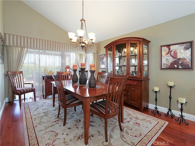 dining space with lofted ceiling, baseboards, wood finished floors, and an inviting chandelier