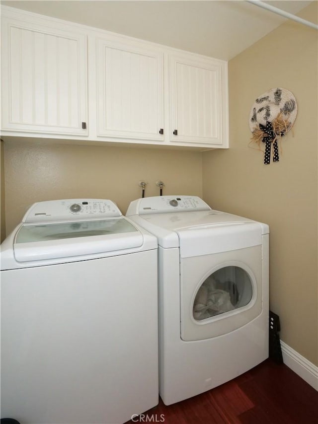 clothes washing area featuring cabinet space, baseboards, washer and clothes dryer, and dark wood-type flooring