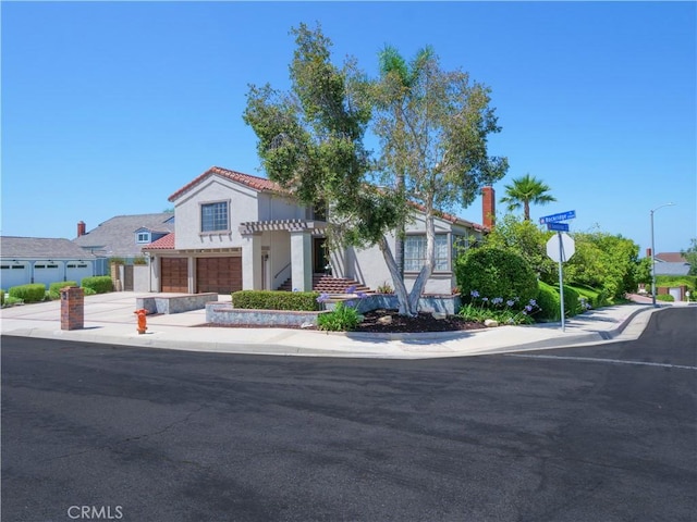 mediterranean / spanish house featuring a garage, stucco siding, concrete driveway, and a tiled roof