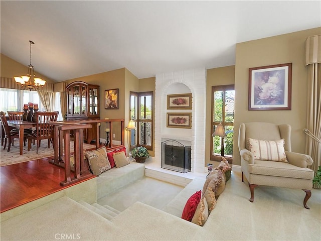 carpeted living area with vaulted ceiling, a brick fireplace, a chandelier, and a wealth of natural light