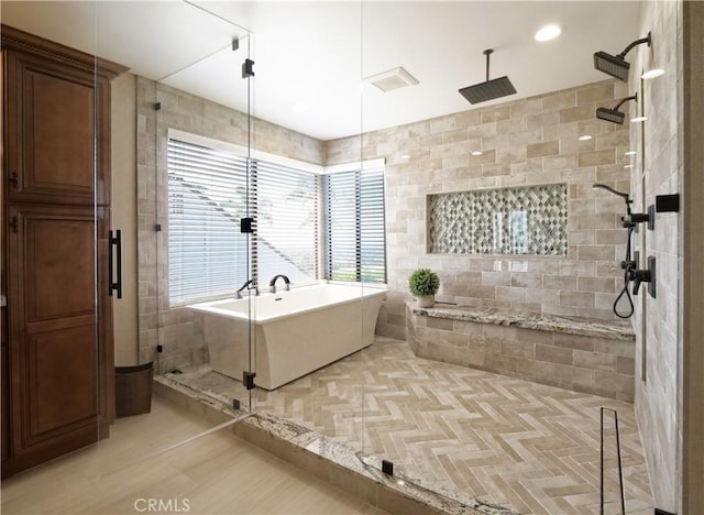 full bathroom with tile walls, a freestanding tub, and a shower stall