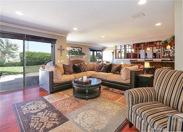 living room with recessed lighting, visible vents, crown molding, and wood finished floors