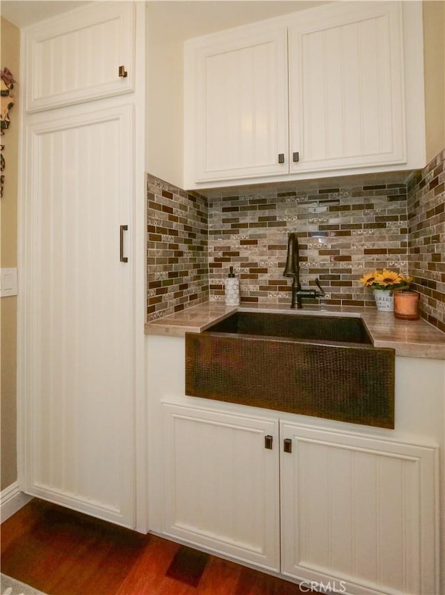 kitchen featuring white cabinets, dark wood finished floors, backsplash, and a sink