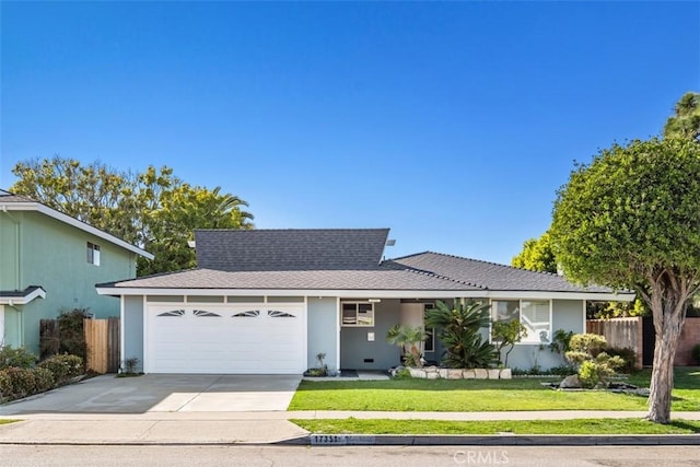 ranch-style house featuring an attached garage, fence, driveway, stucco siding, and a front yard