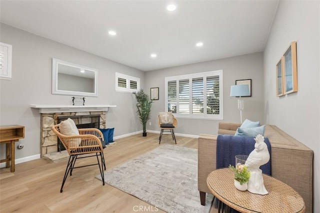 living area featuring baseboards, a stone fireplace, wood finished floors, and recessed lighting