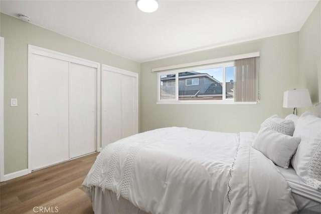 bedroom with wood finished floors and multiple closets