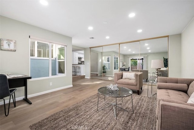 living area with baseboards, wood finished floors, and recessed lighting