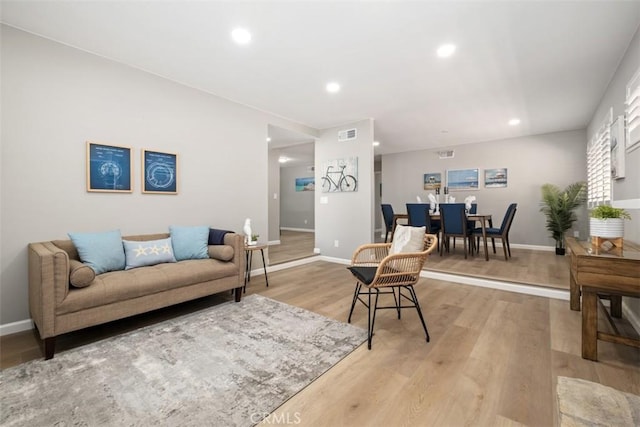 living room with baseboards, light wood-type flooring, visible vents, and recessed lighting