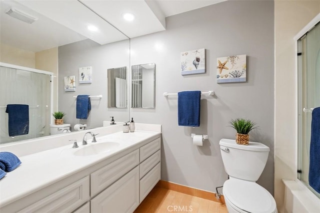 full bathroom featuring a shower with door, toilet, vanity, wood finished floors, and baseboards