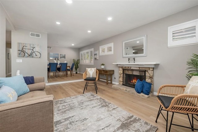 living room with a stone fireplace, visible vents, wood finished floors, and recessed lighting