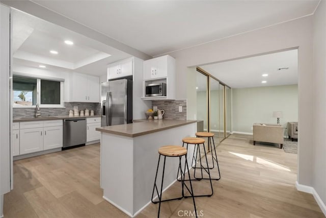 kitchen featuring white cabinets, appliances with stainless steel finishes, a breakfast bar, and a sink