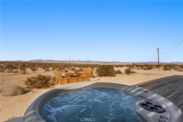 view of swimming pool with an outdoor hot tub, a mountain view, and a desert view