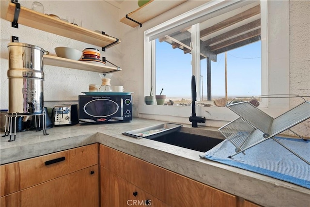 kitchen with light countertops, a sink, and open shelves