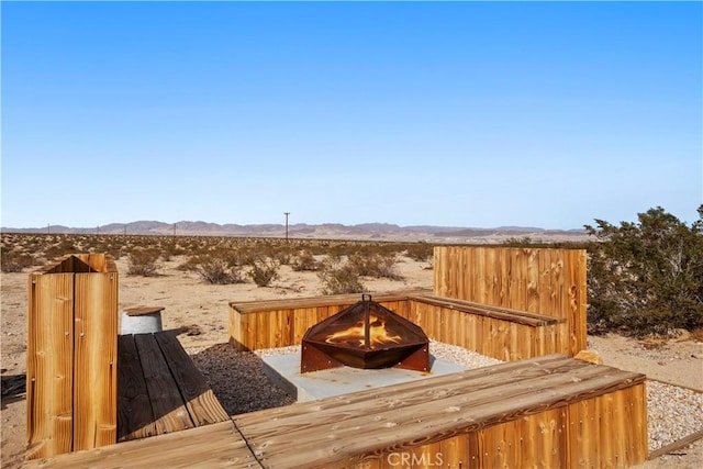 wooden deck with an outdoor fire pit, a desert view, and a mountain view