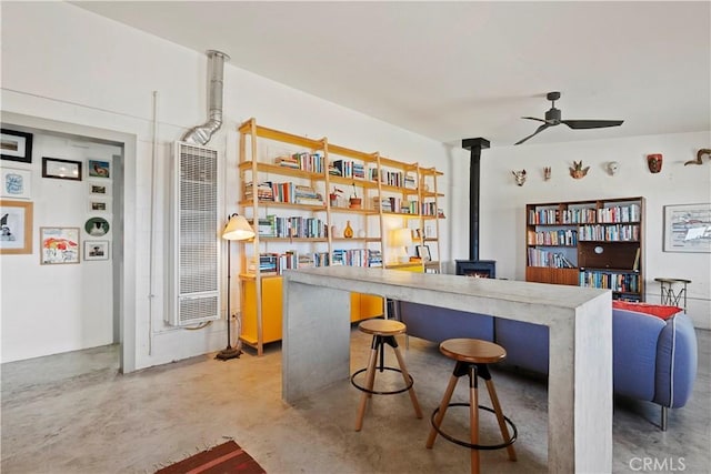 bar with a wood stove, finished concrete floors, a heating unit, and a ceiling fan