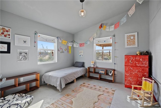 bedroom with unfinished concrete floors and multiple windows