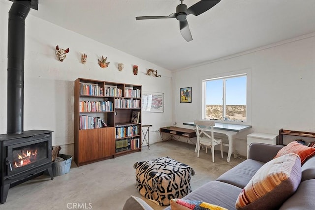 interior space featuring concrete flooring, a wood stove, and a ceiling fan