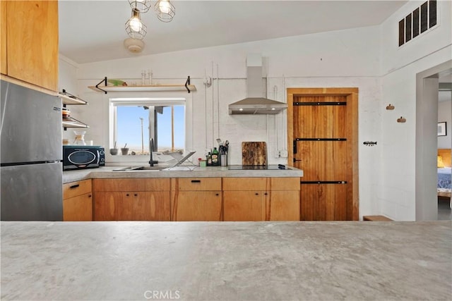 kitchen featuring visible vents, freestanding refrigerator, light countertops, wall chimney range hood, and black microwave