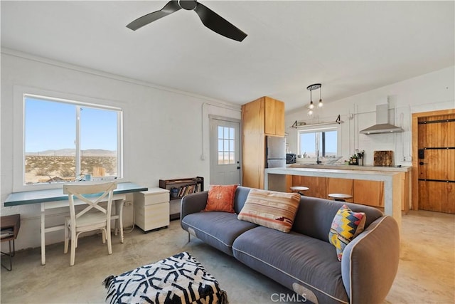 living area with a ceiling fan, plenty of natural light, and concrete floors