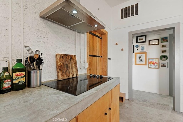 kitchen featuring black electric stovetop, visible vents, concrete floors, and wall chimney exhaust hood