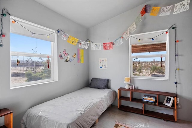 bedroom featuring multiple windows and finished concrete flooring