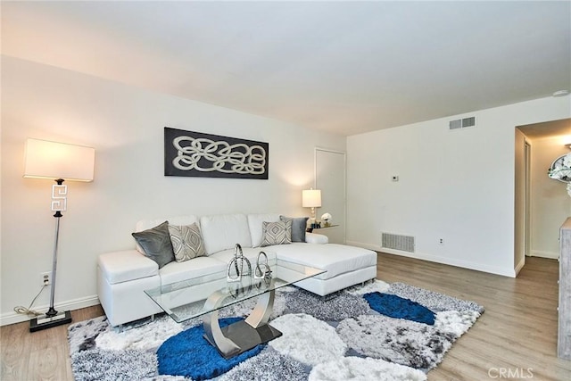 living area with visible vents, baseboards, and wood finished floors