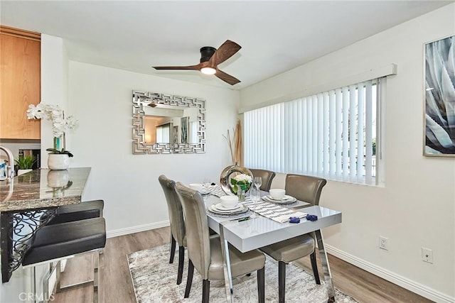 dining area featuring wood finished floors, a ceiling fan, and baseboards