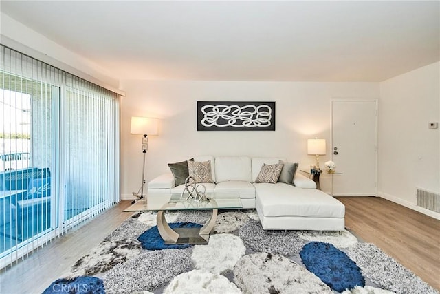 living area with wood finished floors, visible vents, and baseboards