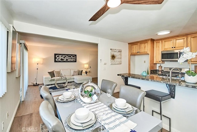 dining space with ceiling fan, light wood finished floors, and baseboards