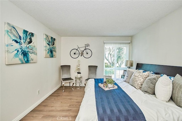 bedroom featuring a textured ceiling, baseboards, and wood finished floors