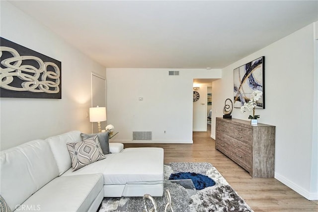 living area featuring light wood-style floors, visible vents, and baseboards