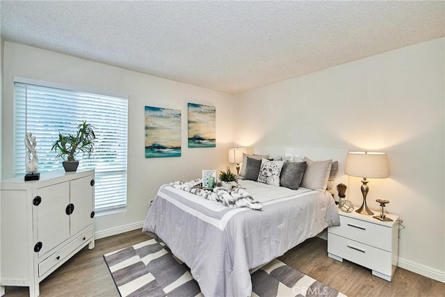 bedroom featuring a textured ceiling, wood finished floors, and baseboards