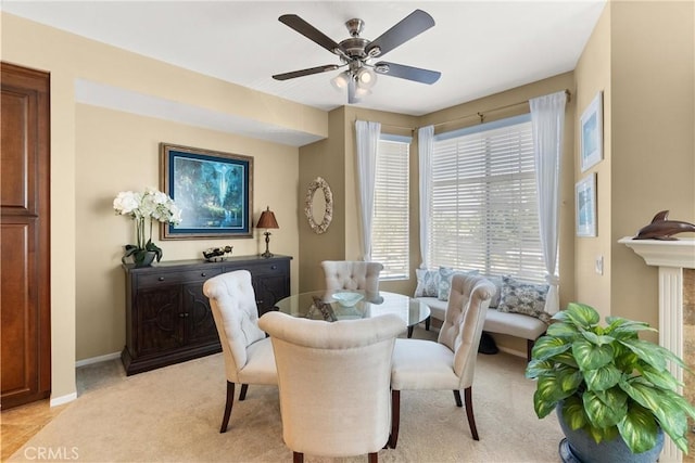 dining space featuring light carpet, baseboards, and a ceiling fan