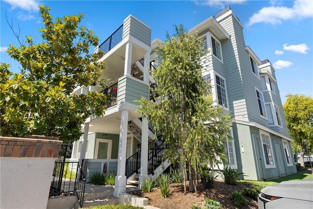 view of front of property with stairs, fence, and stucco siding