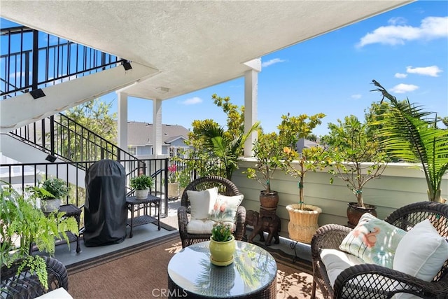 balcony featuring stairs, a grill, and an outdoor living space