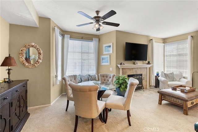 dining room featuring baseboards, a premium fireplace, plenty of natural light, and light colored carpet