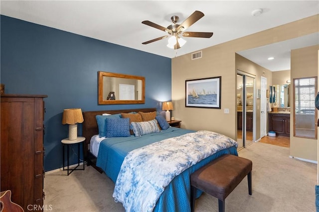 bedroom featuring visible vents, ensuite bathroom, a ceiling fan, light carpet, and baseboards