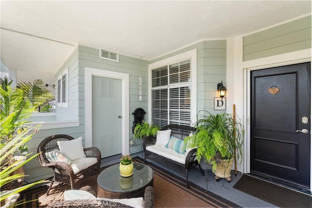 doorway to property featuring covered porch and visible vents