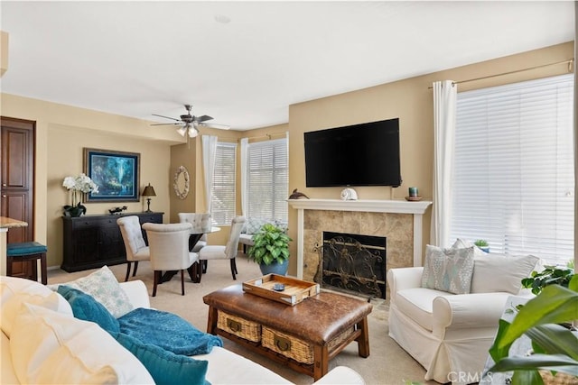 living area with ceiling fan, plenty of natural light, a high end fireplace, and light colored carpet