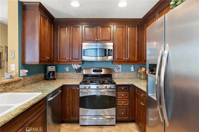 kitchen with light stone countertops, recessed lighting, appliances with stainless steel finishes, and light tile patterned flooring