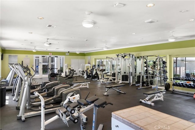 exercise room featuring visible vents, ornamental molding, and a ceiling fan