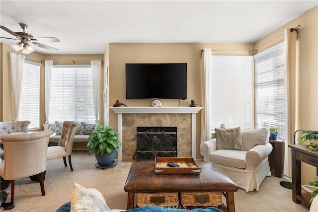 living room with carpet floors, a ceiling fan, and a tiled fireplace