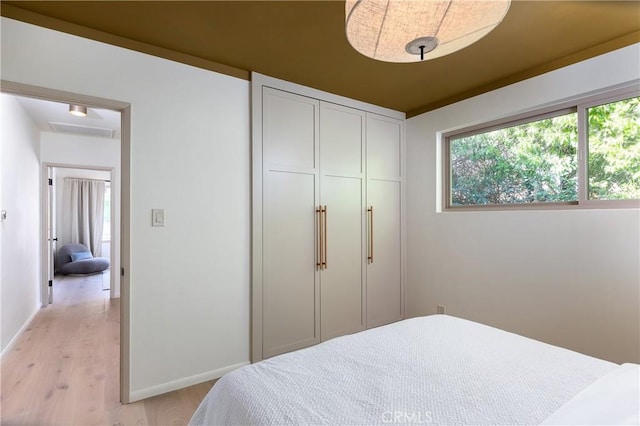 bedroom featuring light wood-type flooring, a closet, and baseboards