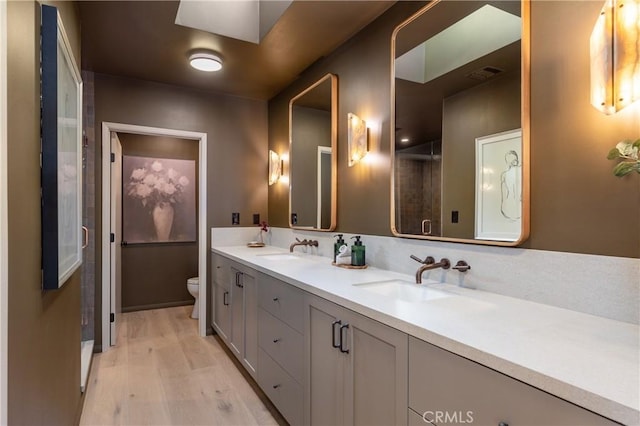 bathroom featuring visible vents, wood finished floors, a sink, and toilet