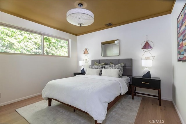 bedroom with visible vents, baseboards, and wood finished floors