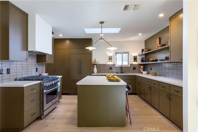 kitchen with light countertops, a skylight, high end stove, and visible vents