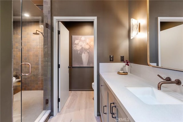 bathroom featuring toilet, a stall shower, wood finished floors, and vanity